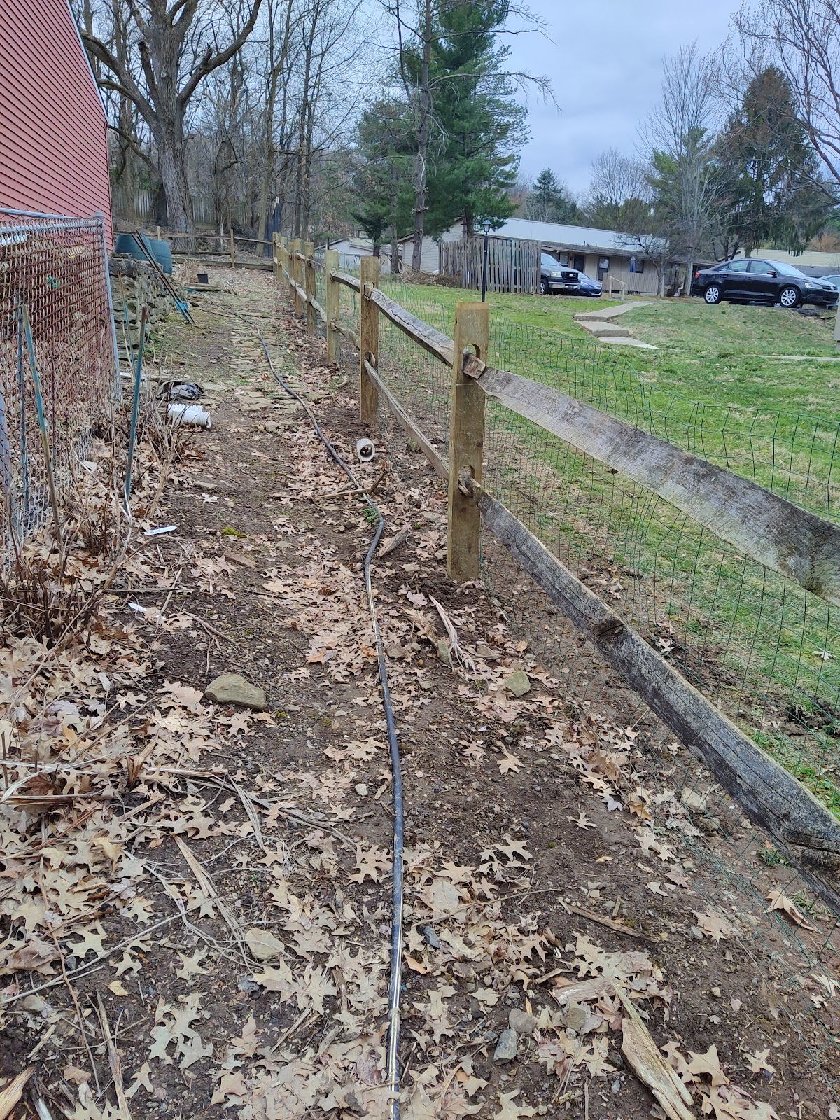 Wood split-rail fence with wire mesh backing along a property line